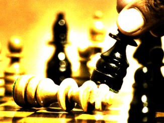 Picture of chess board, king lying down, a hand moving another piece. Hot off the chess, classic game.